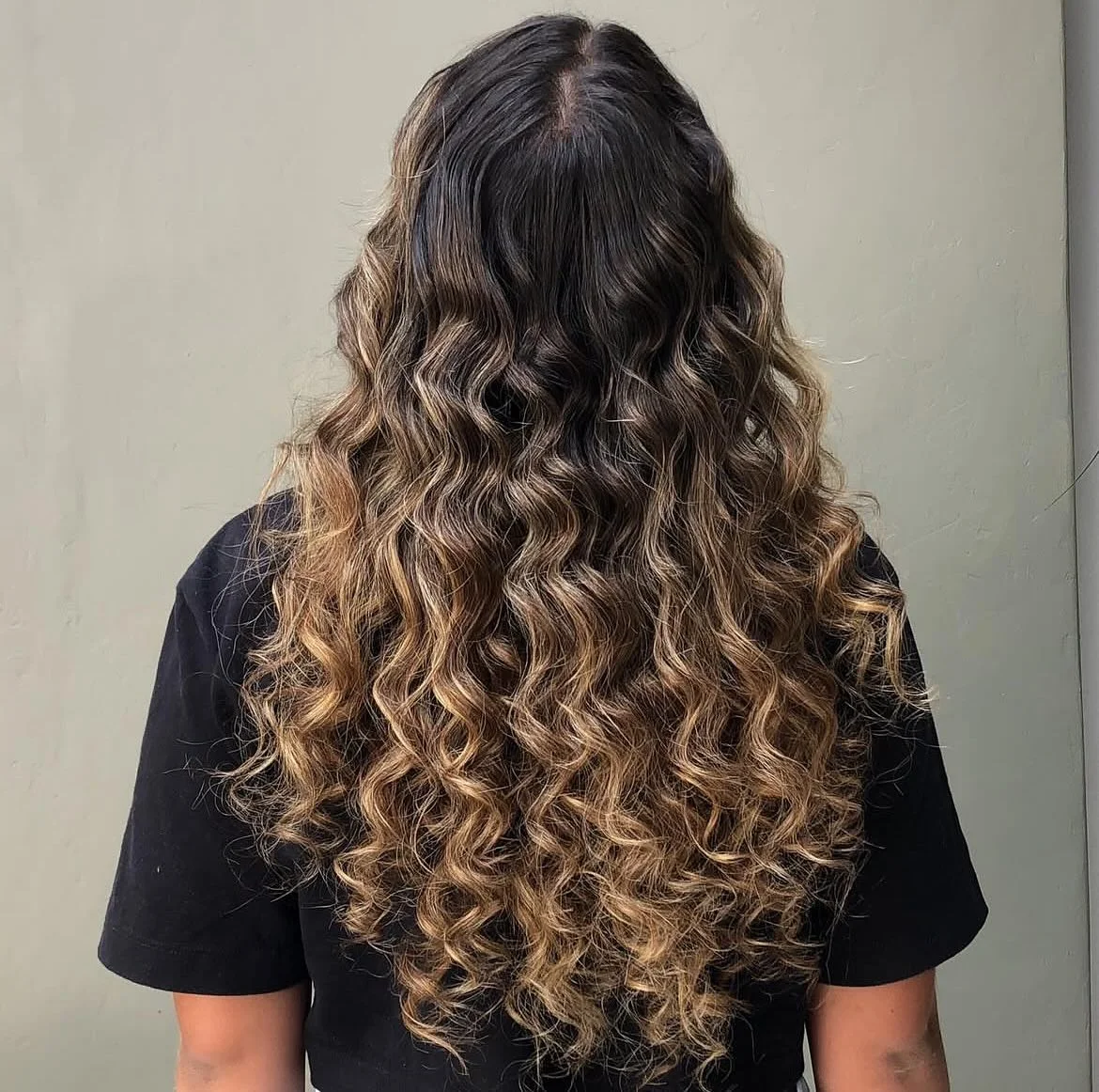 beachy summer hair color for tan skin 2026 Defined Caramel Curls With Deep Brunette Base